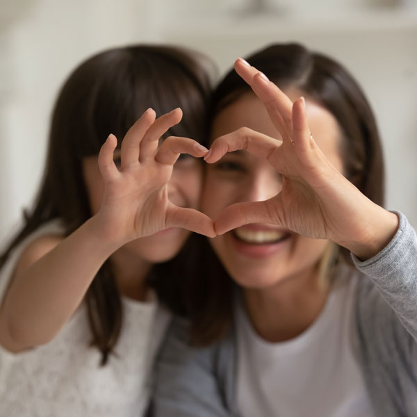 woman and daughter making heart with hands