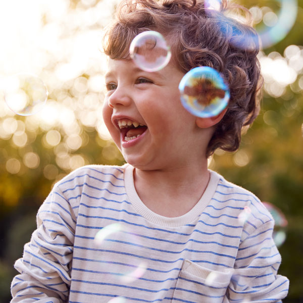 little boy smiling playing with bubbles